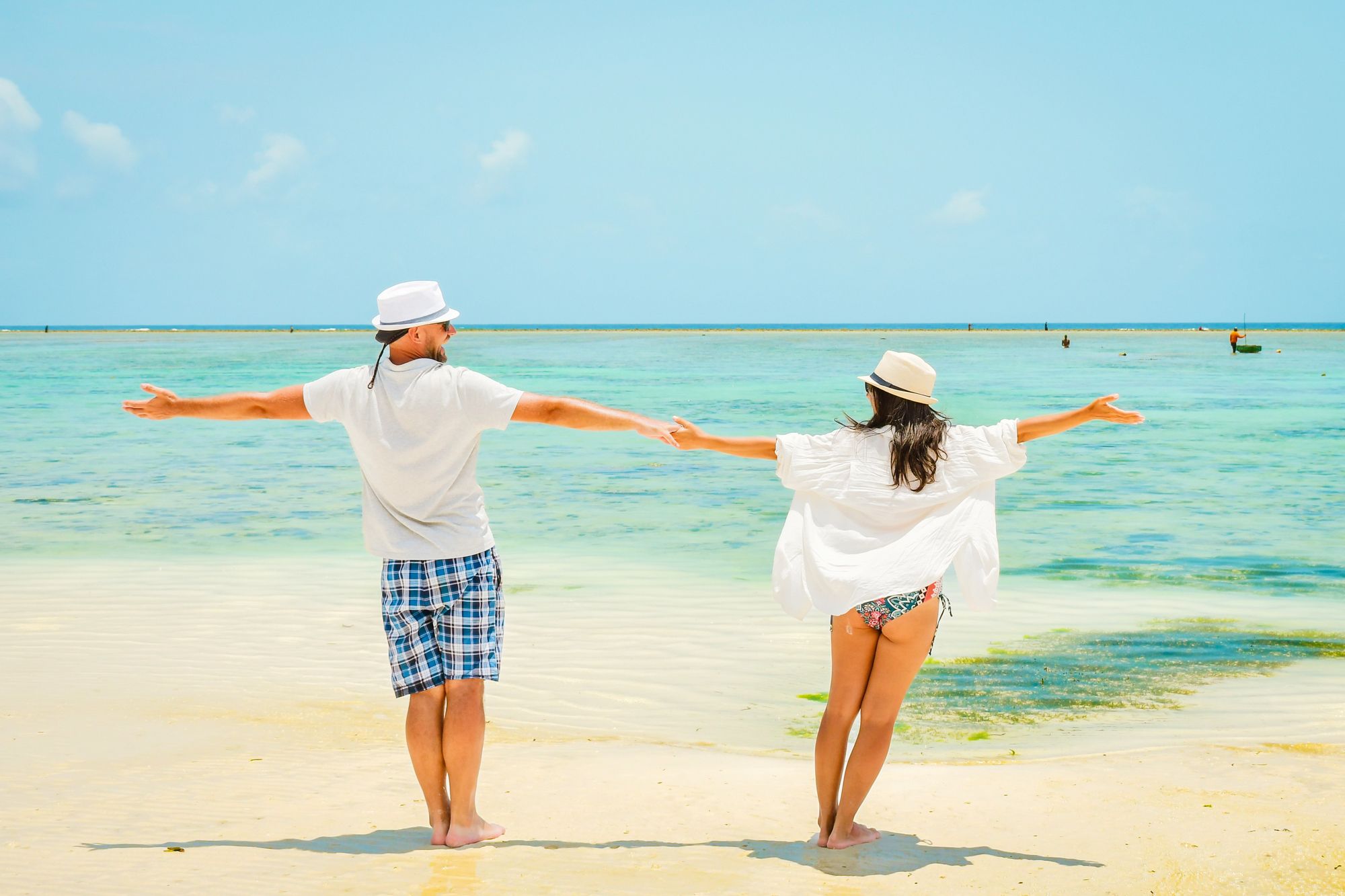 A couple standing with their arms outstretched on an empty beach
